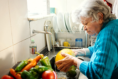 Senior woman disinfecting vegetables in the kitchen